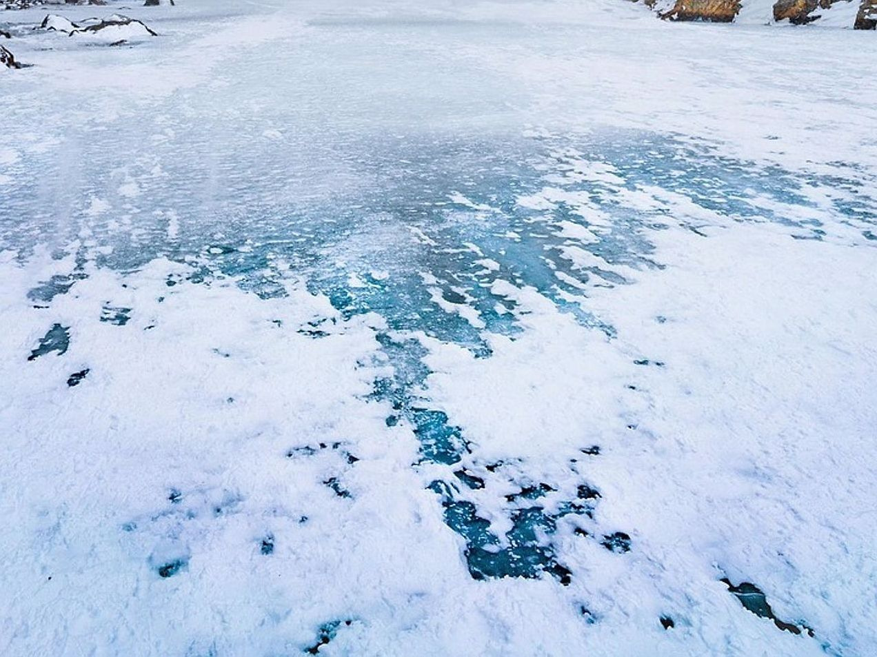 Pescadores en el lago bajo el hielo durante el atardecer